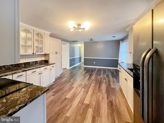 kitchen featuring dark stone countertops, stainless steel fridge, glass insert cabinets, and white cabinets