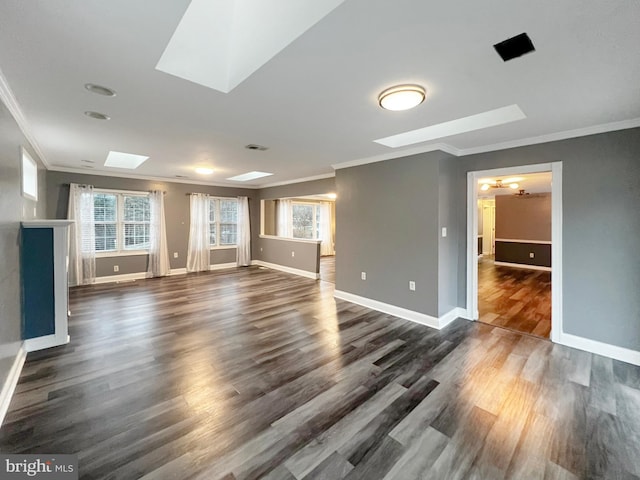 unfurnished living room with ornamental molding, a skylight, dark wood finished floors, and baseboards