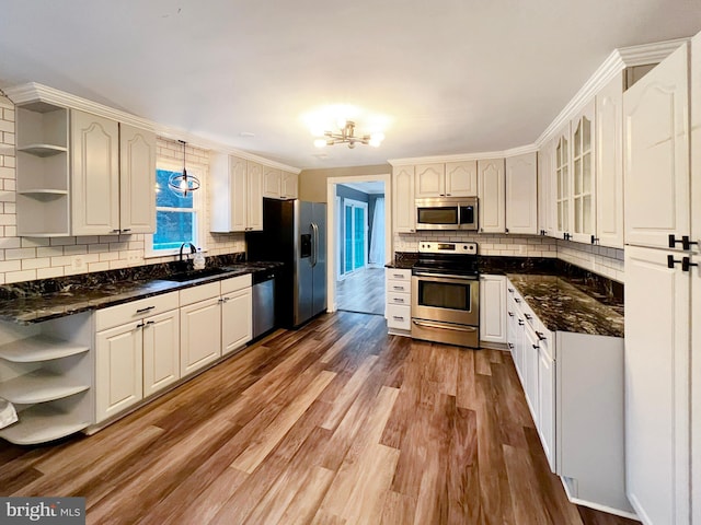 kitchen featuring open shelves, appliances with stainless steel finishes, a sink, and light wood-style floors