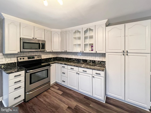 kitchen with appliances with stainless steel finishes, white cabinetry, glass insert cabinets, and dark wood-style floors