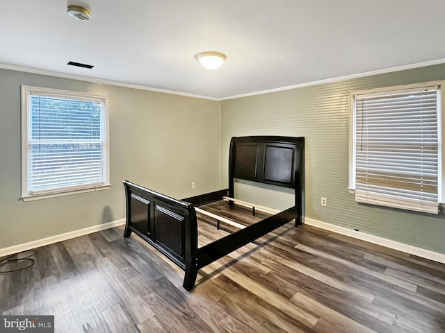 unfurnished bedroom featuring dark wood-style flooring, crown molding, and baseboards