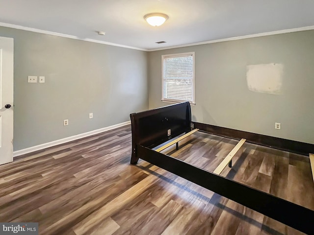 bedroom with baseboards, crown molding, and wood finished floors