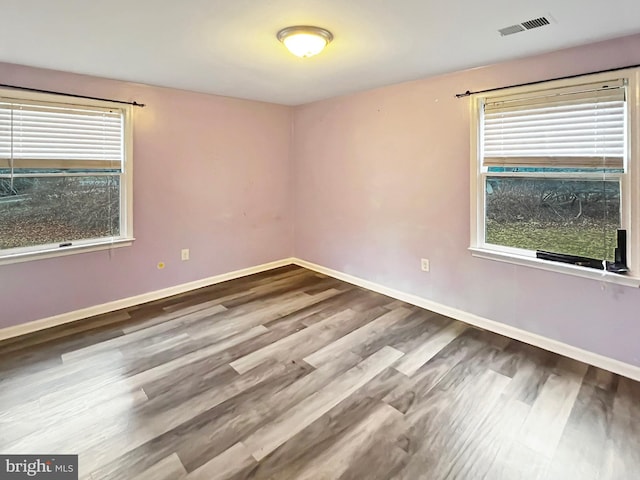 unfurnished room featuring visible vents, baseboards, and wood finished floors