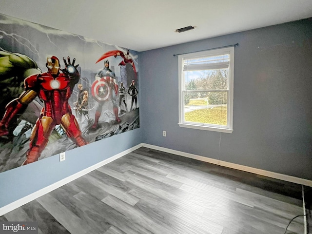 empty room with baseboards, visible vents, and wood finished floors