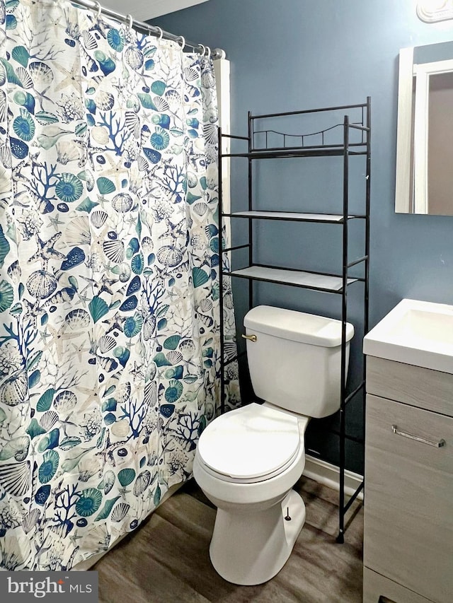 full bathroom with toilet, baseboards, wood finished floors, and vanity