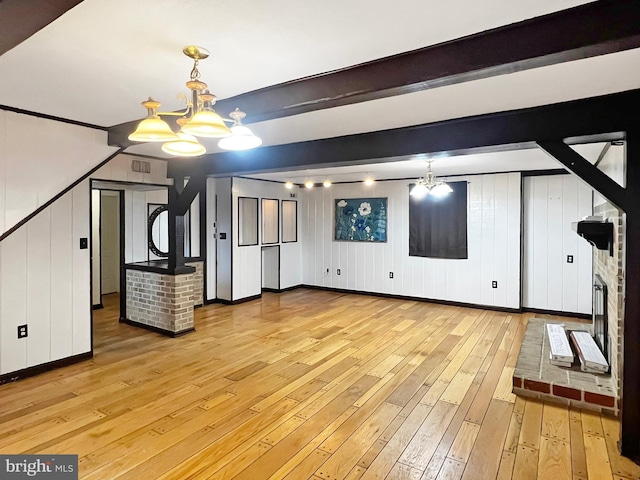 bonus room with a notable chandelier, a fireplace, visible vents, light wood-style floors, and beamed ceiling