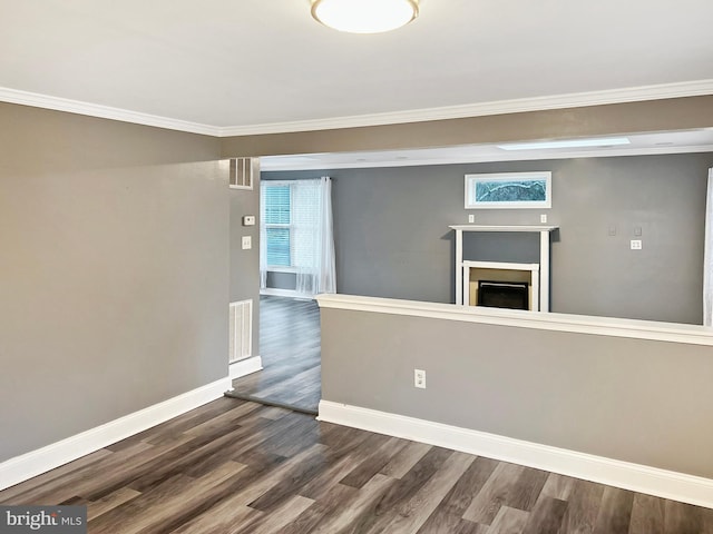 empty room featuring dark wood-style floors, baseboards, a fireplace, and visible vents