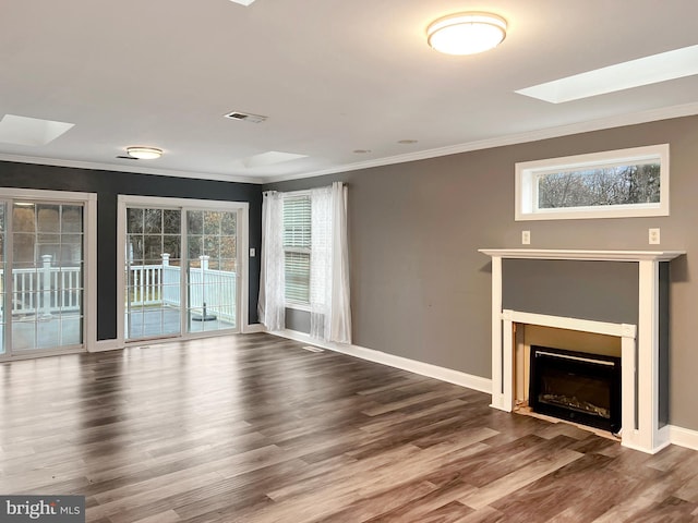 unfurnished living room with a skylight, visible vents, ornamental molding, wood finished floors, and baseboards