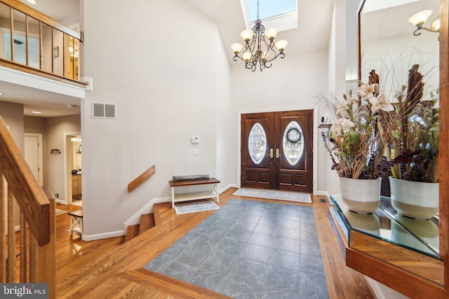 foyer featuring wood-type flooring, a chandelier, and a high ceiling