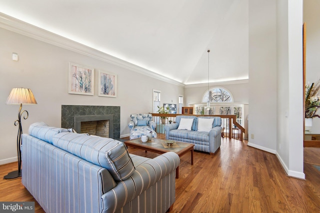 living room with crown molding, high vaulted ceiling, a premium fireplace, and hardwood / wood-style floors