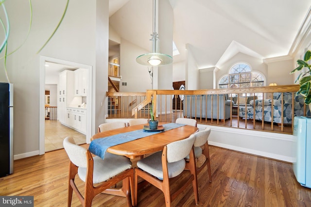 dining area featuring high vaulted ceiling and light hardwood / wood-style floors