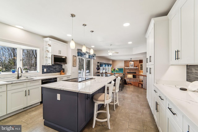 kitchen featuring sink, white cabinetry, a center island, light stone countertops, and black appliances