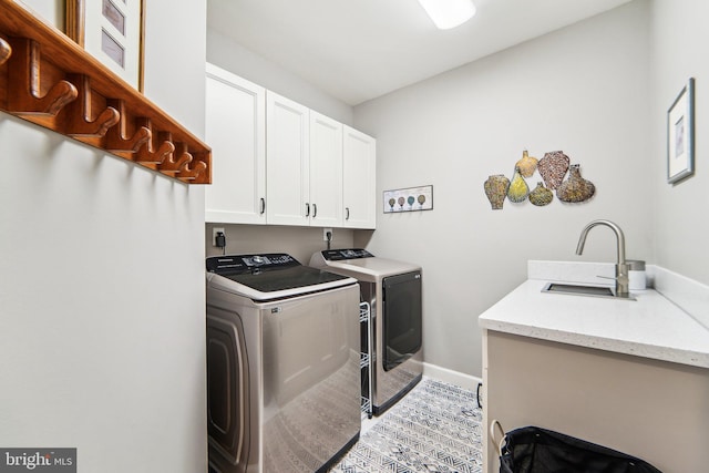 washroom featuring sink, washing machine and dryer, and cabinets