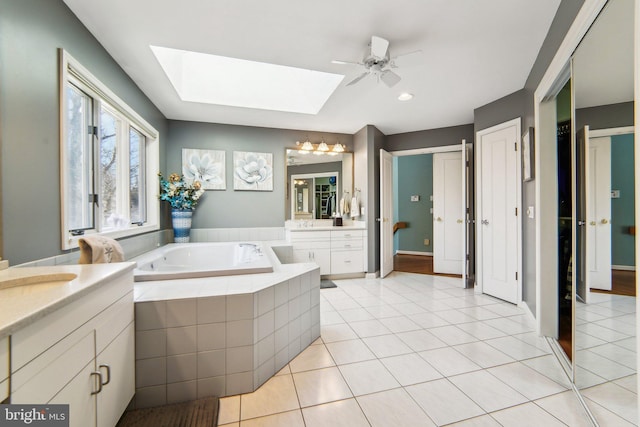 bathroom featuring tiled tub, vanity, tile patterned flooring, and a skylight