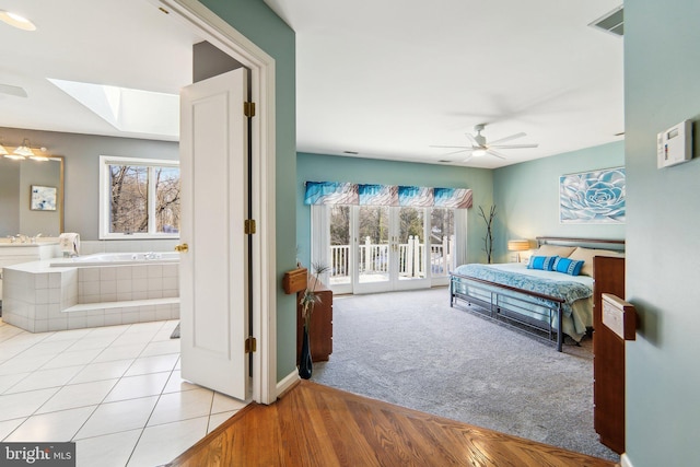 tiled bedroom with multiple windows, sink, access to outside, and a skylight