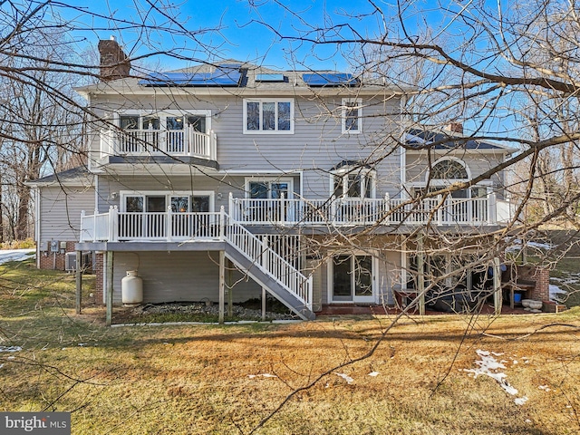 rear view of house featuring central AC, a balcony, and a lawn