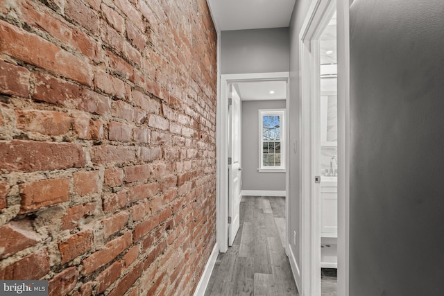 hallway with hardwood / wood-style flooring and brick wall