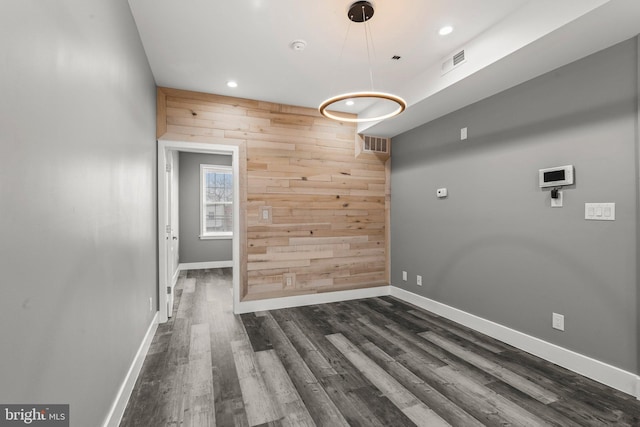 unfurnished room with wood walls and dark wood-type flooring