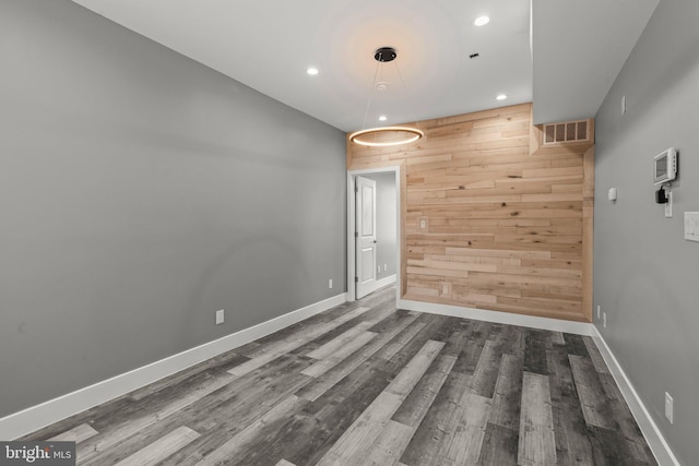 empty room featuring wood walls and dark wood-type flooring