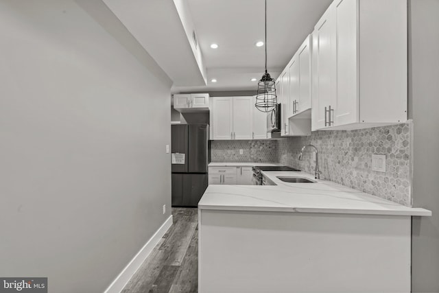 kitchen featuring kitchen peninsula, white cabinetry, decorative light fixtures, and appliances with stainless steel finishes