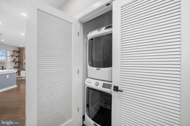 washroom with hardwood / wood-style flooring and stacked washer and clothes dryer