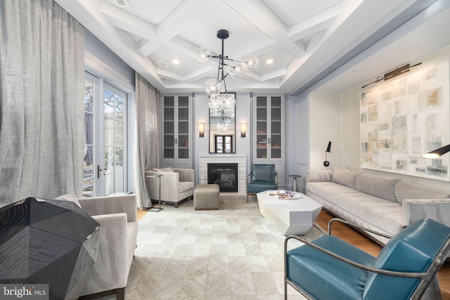 living room with coffered ceiling, a chandelier, and beam ceiling