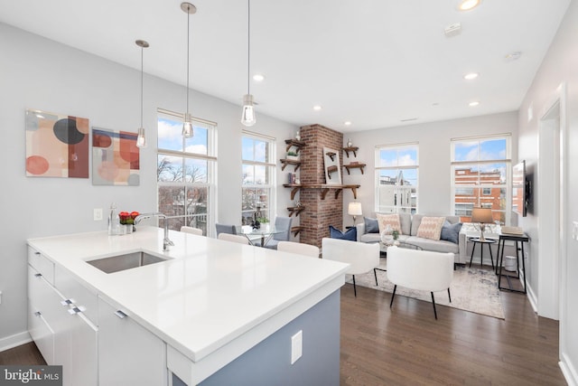 kitchen with decorative light fixtures, white cabinetry, sink, kitchen peninsula, and a healthy amount of sunlight