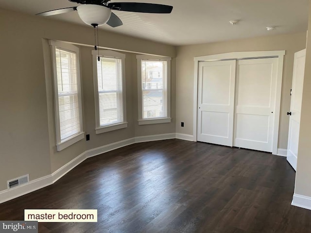 unfurnished bedroom featuring dark hardwood / wood-style floors, a closet, and ceiling fan