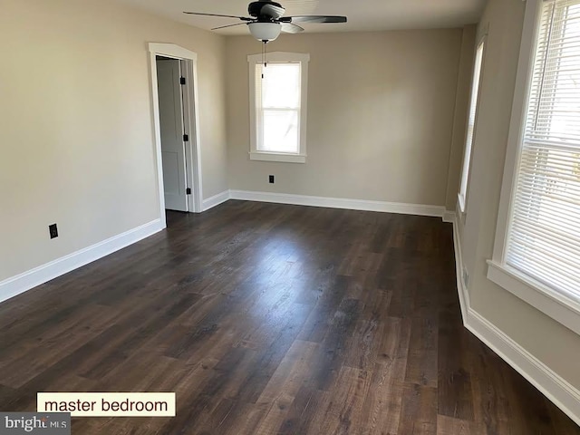 empty room with dark hardwood / wood-style floors, a wealth of natural light, and ceiling fan