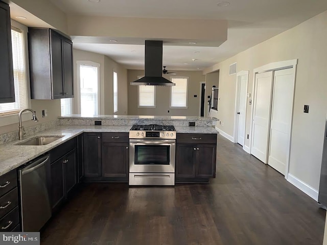 kitchen with appliances with stainless steel finishes, sink, island exhaust hood, kitchen peninsula, and light stone countertops