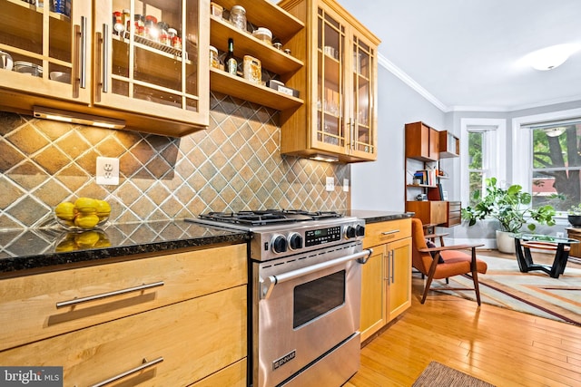 kitchen with dark stone countertops, backsplash, ornamental molding, light wood-type flooring, and stainless steel range with gas cooktop