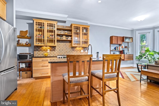 kitchen featuring crown molding, light wood-type flooring, tasteful backsplash, and stainless steel appliances