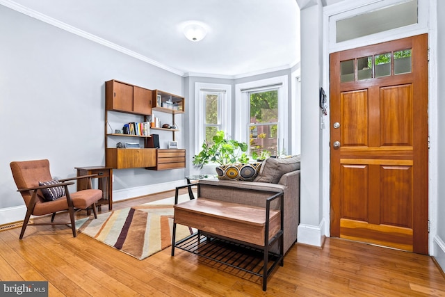 living area with light hardwood / wood-style floors and ornamental molding