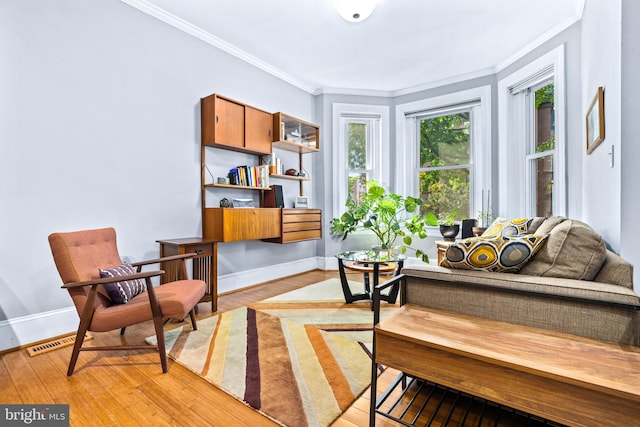 living area with crown molding and light hardwood / wood-style flooring