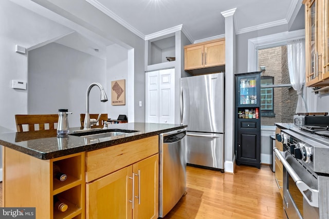 kitchen with stainless steel appliances, dark stone countertops, sink, a center island with sink, and crown molding