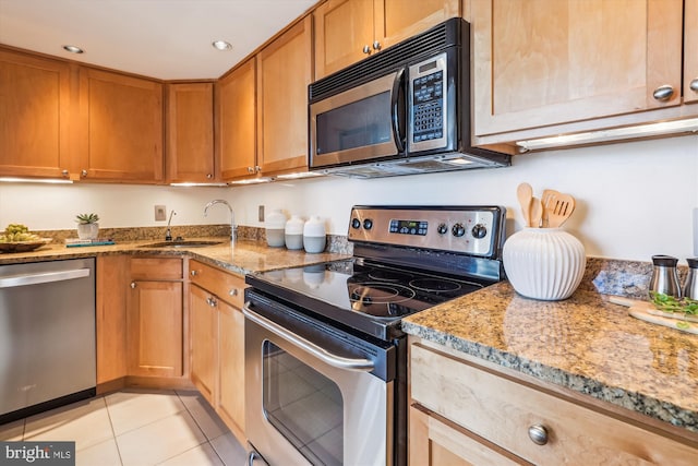 kitchen with light stone counters, sink, light tile patterned floors, and appliances with stainless steel finishes