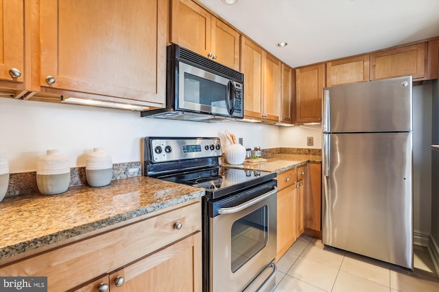 kitchen with appliances with stainless steel finishes, light tile patterned floors, and light stone counters