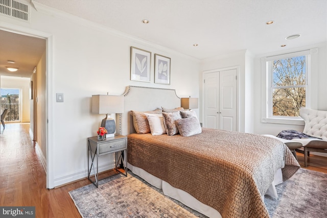 bedroom with crown molding, light wood-type flooring, and a closet