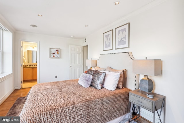 bedroom featuring hardwood / wood-style flooring, ornamental molding, and connected bathroom