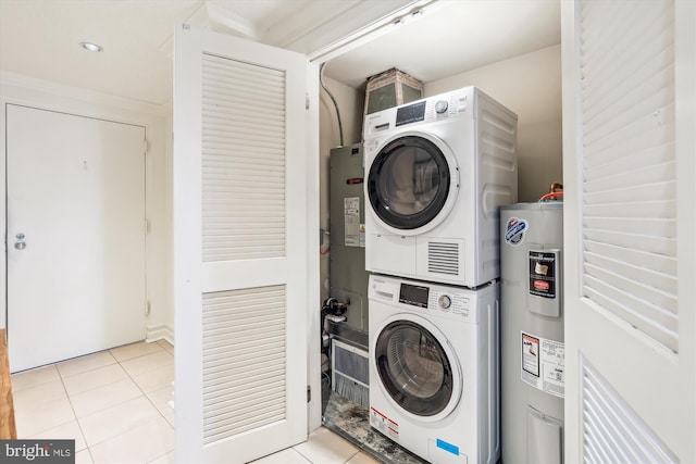 laundry area featuring water heater, stacked washing maching and dryer, and light tile patterned floors