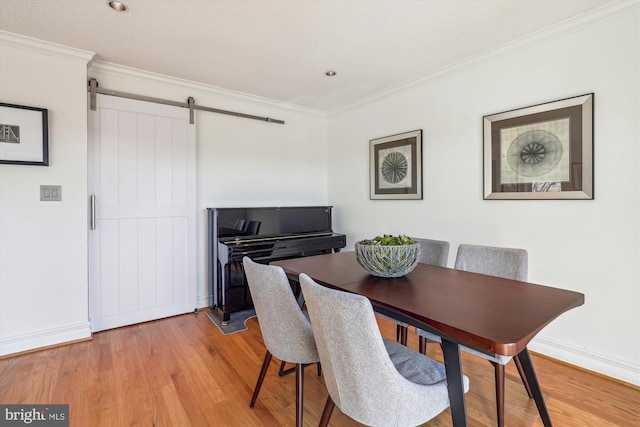 dining room with ornamental molding, a barn door, and wood-type flooring