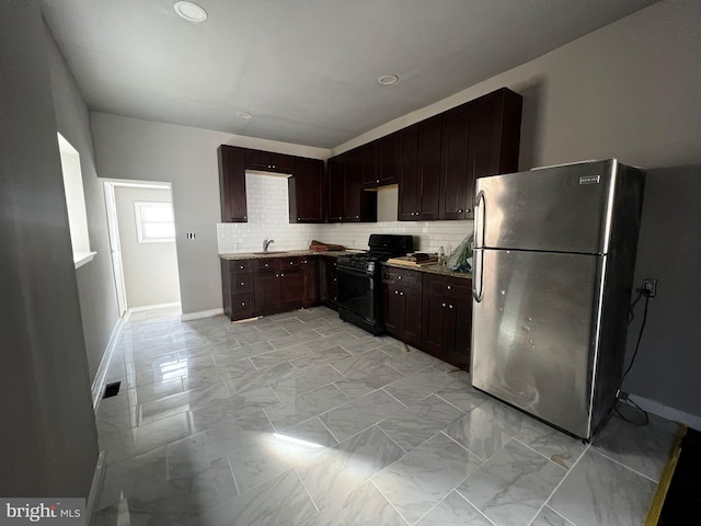 kitchen with tasteful backsplash, sink, dark brown cabinets, stainless steel refrigerator, and black range with gas stovetop