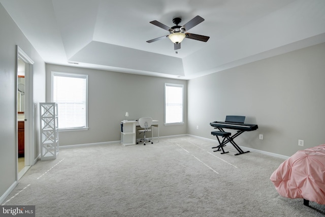 interior space featuring ceiling fan, a tray ceiling, and light carpet