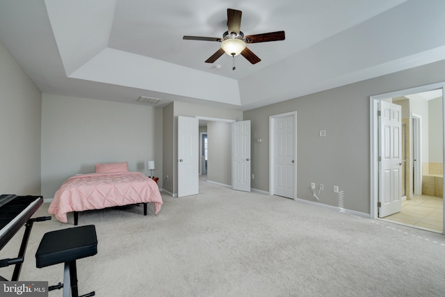 carpeted bedroom with connected bathroom, a raised ceiling, and ceiling fan