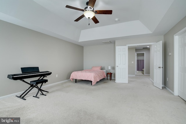 carpeted bedroom with a raised ceiling and ceiling fan