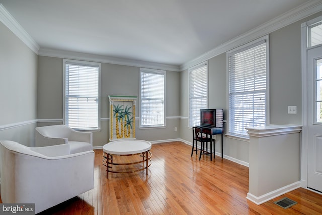 sitting room with ornamental molding and light hardwood / wood-style floors