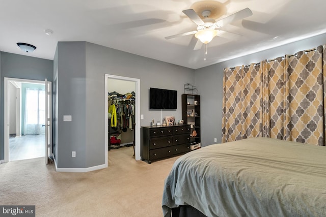 bedroom with light carpet, a closet, ceiling fan, and a walk in closet