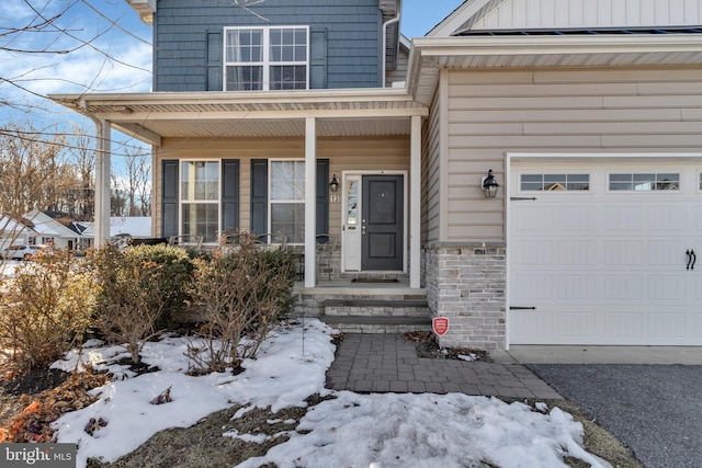 snow covered property entrance with a garage