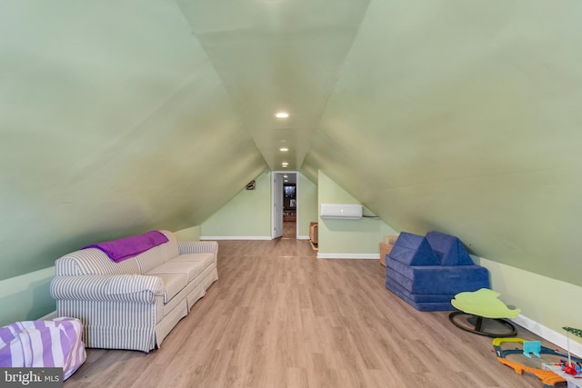 interior space featuring light hardwood / wood-style floors, a wall unit AC, and lofted ceiling