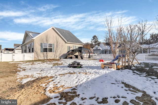 snow covered rear of property featuring an outdoor fire pit, a gazebo, and a playground